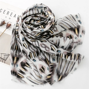 Detail of ikat geometric pattern scarf with gold foil stripes and fringed edges