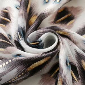Macro shot of feather pattern scarf with gold foil dots and soft linen texture
