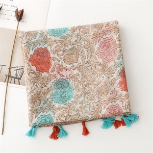 Detail of vintage floral print shawl with red and blue tassels on a white background