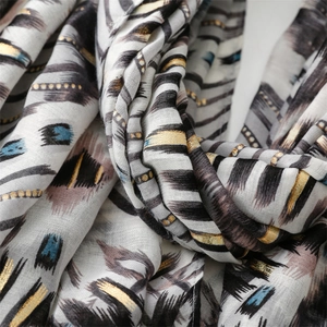 Macro detail of scarf featuring gold foil geometric patterns on soft linen texture