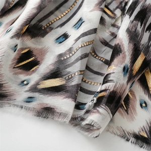 Detailed view of scarf featuring gold foil geometric patterns and soft frayed edges