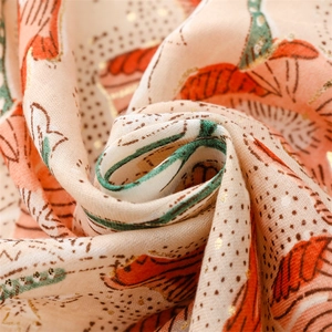 Detail of soft linen-touch scarf featuring golden peony print and fringe texture