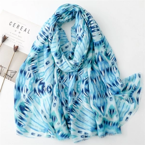 Detail of blue and white ethnic scarf with silver threads and fringed edges over a book