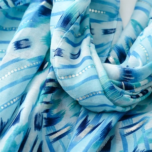 Macro detail of blue geometric scarf fabric with gold foil dots and soft texture