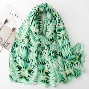 Detail of green leaf print scarf with gold foil accents and delicate fringe edges