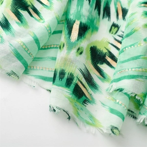 Macro shot of cotton linen scarf with gold foil accents and abstract green geometric pattern