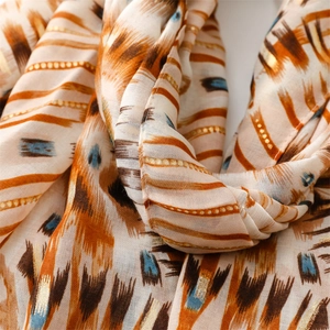 Macro detail of geometric ikat print scarf with elegant gold foil accents and soft texture