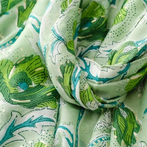 Detail of light green scarf with dark green floral prints and gold foil accents