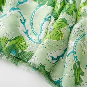 Macro detail of gold floral peony print on light green cotton linen scarf with raw edges