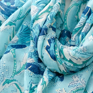 Detail of light blue floral scarf featuring golden peony print and linen-feel texture
