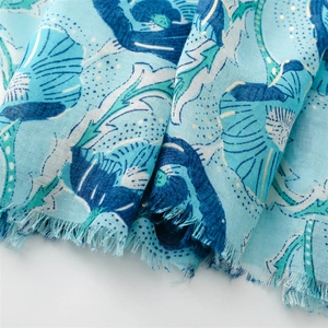 Close-up of blue floral cotton linen scarf featuring elegant gold foil details and raw fringe