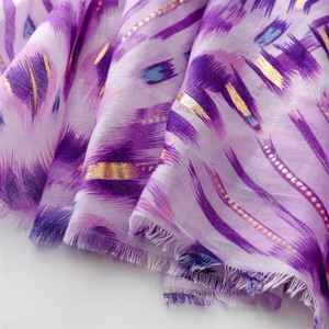 Macro view of purple gradient linen-feel scarf featuring gold foil and fringe details