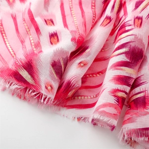 Macro detail of red cotton linen scarf showing gold foil geometric print and frayed edges