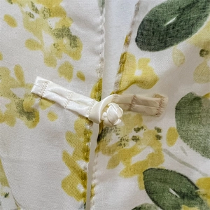Detailed close-up of traditional Chinese button on floral silk shawl with breathable texture