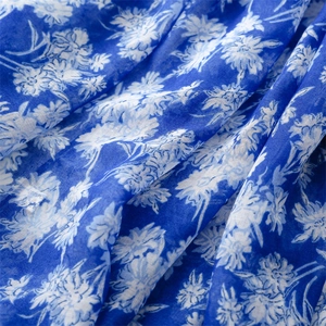 Détail macro d'une écharpe en mousseline bleue avec imprimé marguerites et texture de tissu