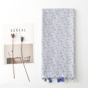 Lightweight floral linen-feel scarf with blue blossoms and tassels on white background