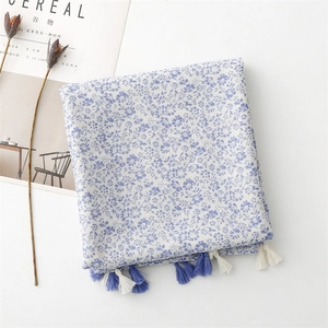 Detailed shot of white floral cotton scarf with blue tassels and vintage pattern