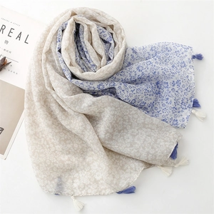 Detail of light floral cotton linen scarf with blue ombre effect and tassel fringe