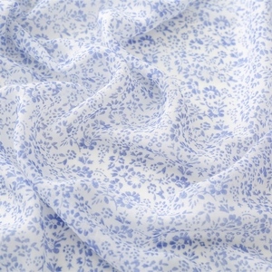 Detailed macro shot of blue floral print on lightweight white linen texture fabric