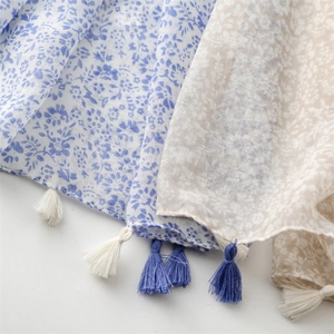 Detail of floral linen-feel scarf with blue and beige patterns and decorative tassels