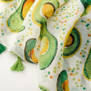 Close-up of lightweight white scarf featuring avocado print and green tassel edges