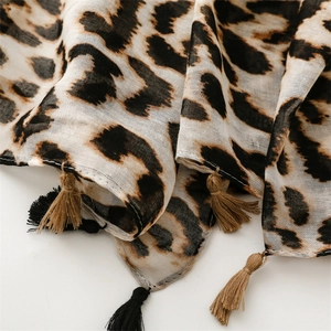 Detail of leopard print scarf fabric showing cotton-linen texture and black fringe tassels