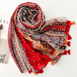 Detailed view of bohemian floral pattern and dual-color tassels on a red summer shawl