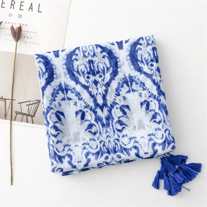 Detail of blue and white floral scarf with tassels and breathable linen-cotton texture