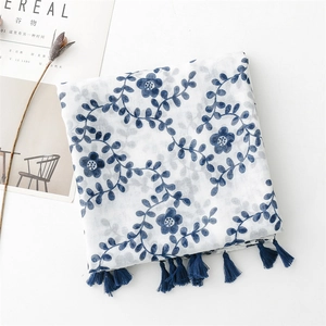 Detail of floral print scarf with blue tassel fringe on white minimalist background