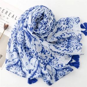Detail of blue and white floral scarf with decorative tassels on a minimalist setting