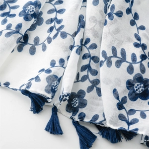 Close-up of blue floral print on white cotton-linen scarf with tassel edge detail