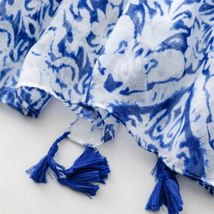 Close-up of blue and white floral scarf with cotton linen texture and tassel fringe