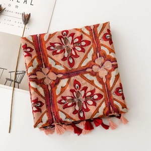 Detail of bohemian floral shawl with tassels on white desk with dried flowers