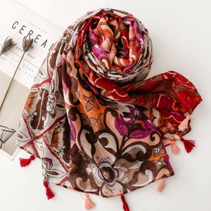 Detail of ethnic floral print scarf with soft tassels and breathable fabric texture