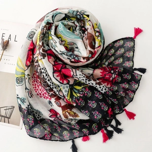 Close-up of colorful floral print scarf with pink and black tassels on white background