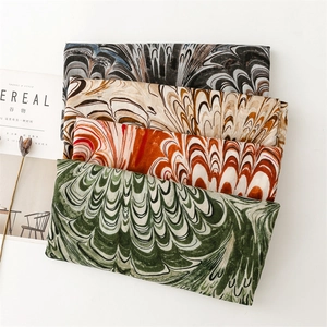 Macro shot of layered scarves featuring textured peacock feather prints on a white desk