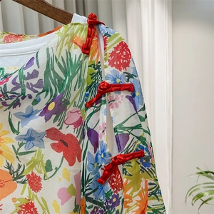 Detail of red Chinese frog buttons and colorful floral print on the sleeve of a shawl