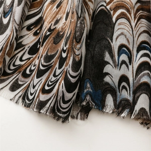 Detail of bohemian scarf with feather pattern and natural fringe edges in brown and blue