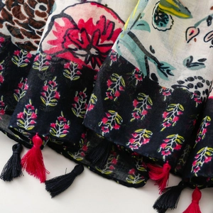 Detailed close-up of floral scarf fabric with vibrant red flowers and decorative tassels