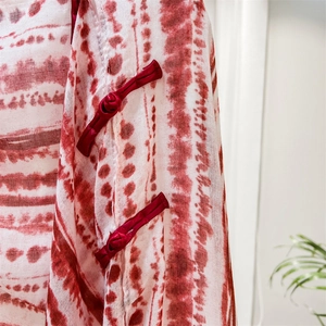 Macro shot of traditional red frog buttons and red-white tie-dye ethnic fabric texture