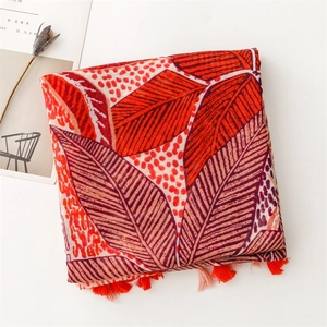 Close-up of red and orange leaf pattern scarf with soft cotton-linen feel and fringe trim