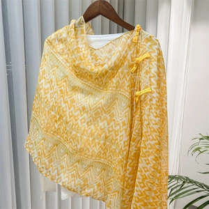 Detail of yellow ethnic geometric pattern shawl with traditional Chinese knot buttons
