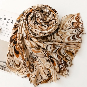 Close-up of earth tone scarf featuring marble prints and delicate frayed edges