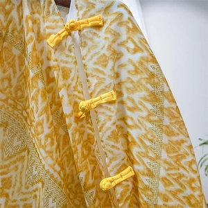 Detailed view of yellow traditional frog buttons and geometric print on a thin shawl