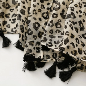 Détail de la texture du foulard léopard avec des franges à glands noirs élégants
