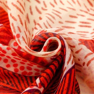 Macro detail of cotton-linen feel scarf showing orange leaf pattern and soft fabric texture