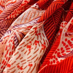 Detail of red and orange leaf pattern scarf with dots and soft cotton-linen texture
