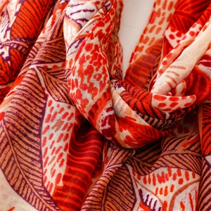 Detailed texture of cotton-linen feel shawl with orange leaf print and soft draping