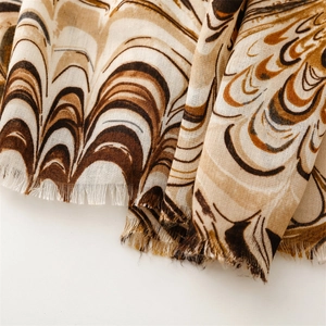 Detail of pashmina scarf featuring earthy tones and abstract wave patterns with raw edges