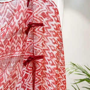 Close-up of red velvet frog button and geometric wave pattern on silk shawl